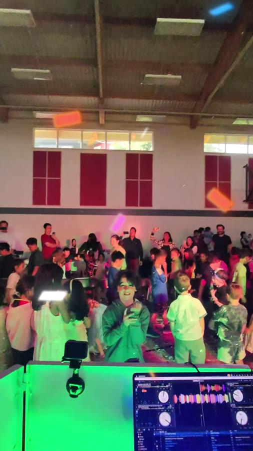 DJ booth and dance lights over a packed gym